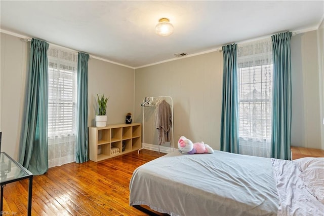 bedroom with ornamental molding, hardwood / wood-style flooring, and visible vents