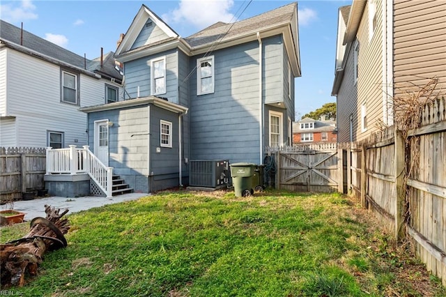 rear view of property with a fenced backyard, a lawn, and central air condition unit