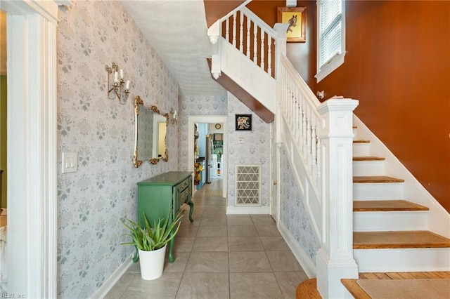 staircase with wallpapered walls, baseboards, and tile patterned floors