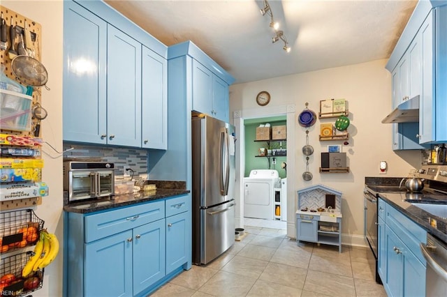 kitchen with light tile patterned floors, backsplash, appliances with stainless steel finishes, dark stone countertops, and blue cabinets