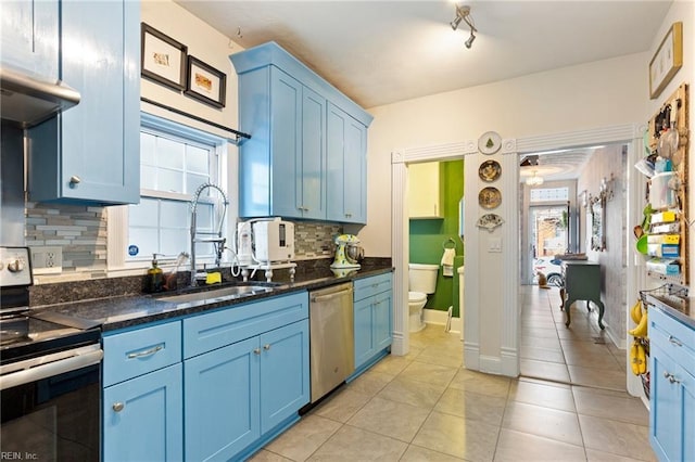 kitchen featuring blue cabinets, light tile patterned floors, appliances with stainless steel finishes, and a sink