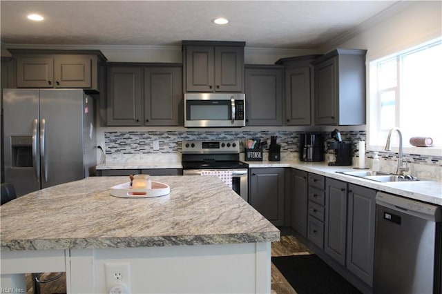 kitchen with light countertops, appliances with stainless steel finishes, a sink, and gray cabinetry