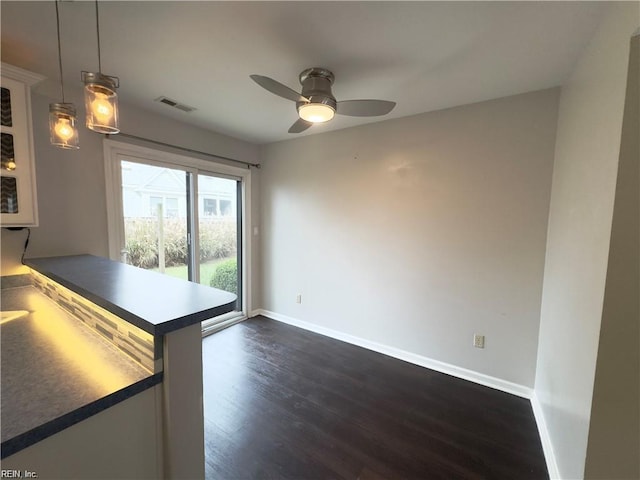 unfurnished dining area with a ceiling fan, baseboards, visible vents, and dark wood-style flooring