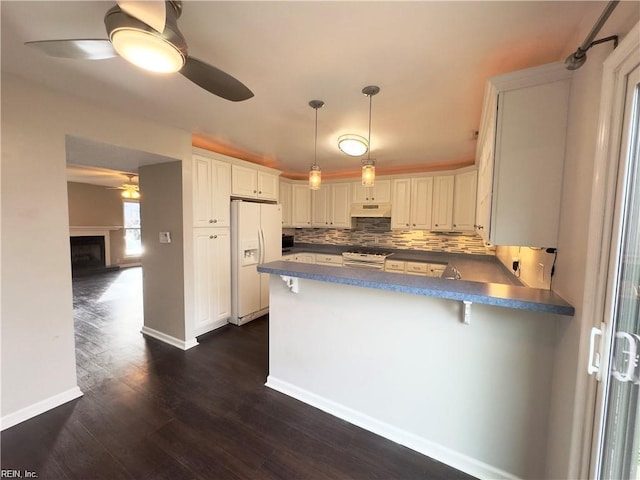 kitchen featuring tasteful backsplash, dark countertops, ceiling fan, white appliances, and a peninsula