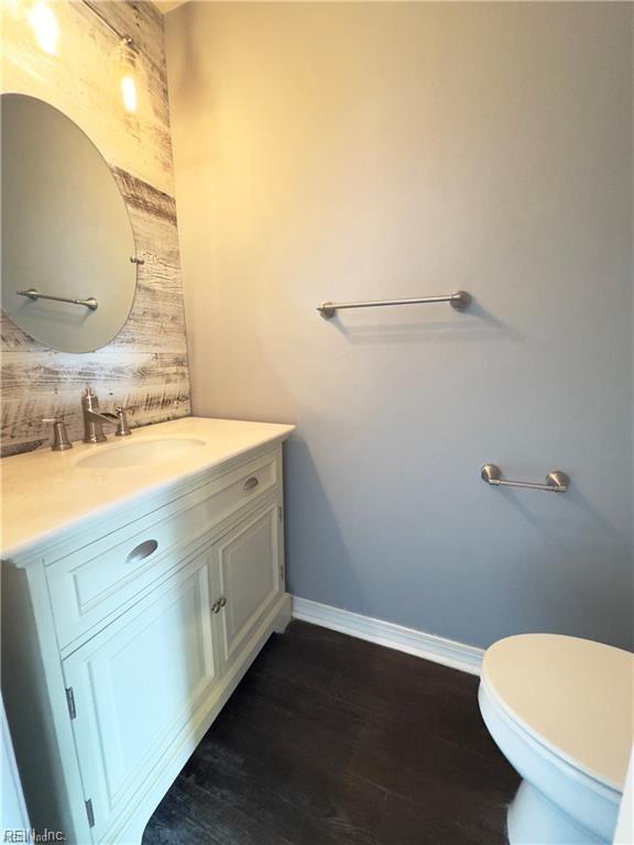 bathroom with toilet, vanity, baseboards, and wood finished floors