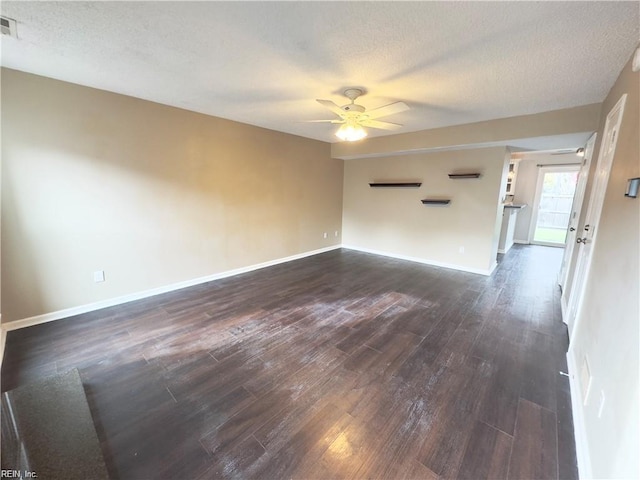 empty room featuring visible vents, dark wood-type flooring, a ceiling fan, a textured ceiling, and baseboards