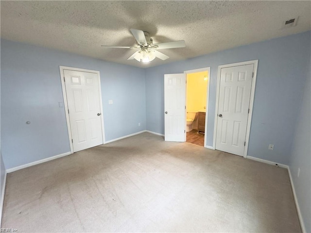 unfurnished bedroom featuring a textured ceiling, carpet floors, visible vents, and baseboards