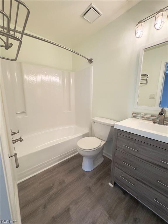 full bath featuring shower / bathtub combination, toilet, wood finished floors, vanity, and visible vents