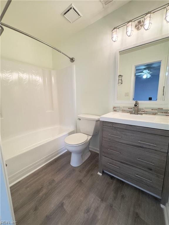 bathroom with toilet, wood finished floors, vanity, visible vents, and tub / shower combination