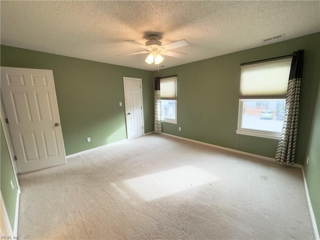 unfurnished room featuring baseboards, ceiling fan, a textured ceiling, and light colored carpet