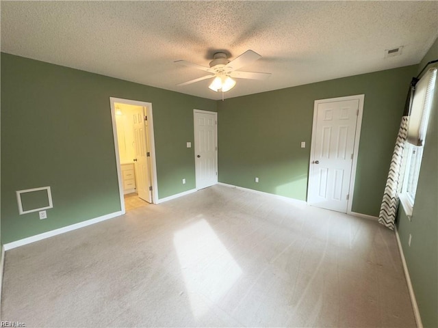 unfurnished bedroom with light colored carpet, ensuite bathroom, ceiling fan, a textured ceiling, and baseboards