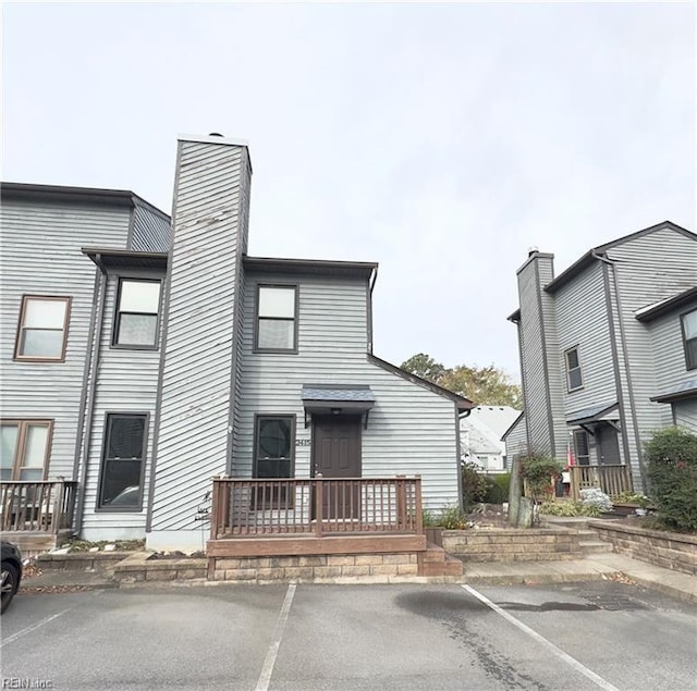 view of front of property featuring uncovered parking and a chimney