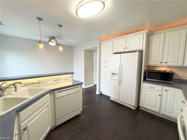 kitchen with white appliances, a sink, white cabinetry, hanging light fixtures, and dark wood-style floors