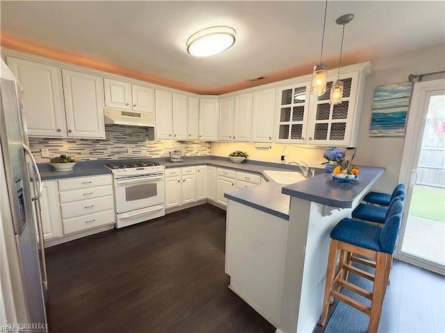 kitchen featuring white range with gas cooktop, stainless steel fridge, a peninsula, under cabinet range hood, and a sink