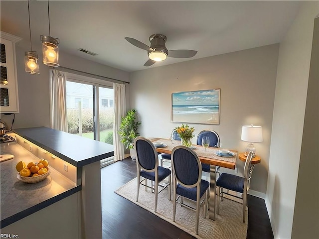 dining space with dark wood-type flooring, visible vents, baseboards, and a ceiling fan