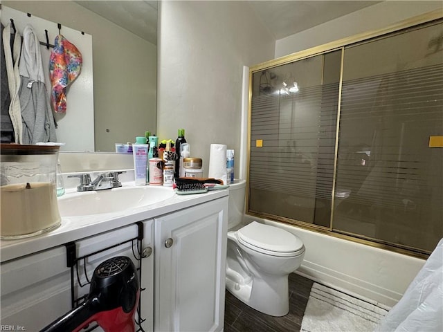 full bath featuring vanity, toilet, and bath / shower combo with glass door