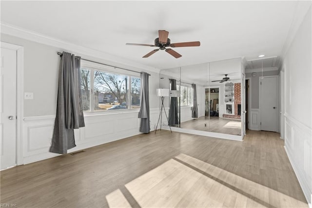 unfurnished room with light wood-style flooring, a decorative wall, visible vents, attic access, and crown molding