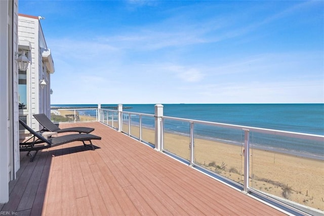 wooden terrace featuring a water view and a view of the beach