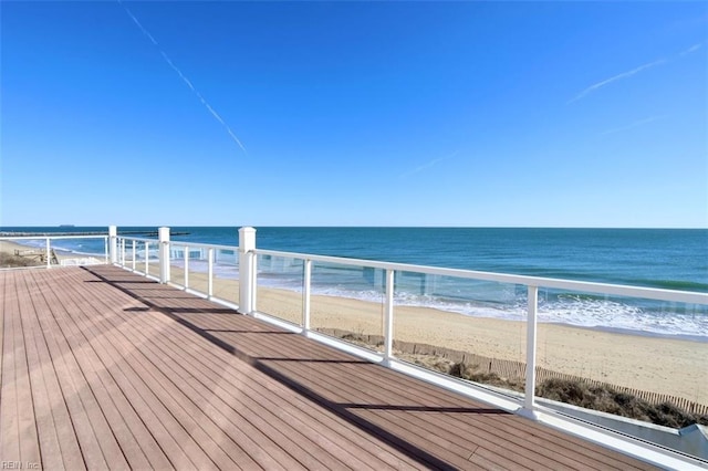 wooden deck featuring a water view and a beach view