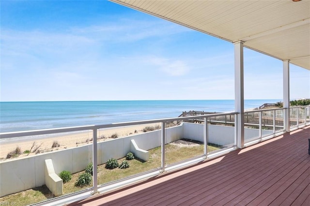 wooden terrace with a water view, fence, and a beach view