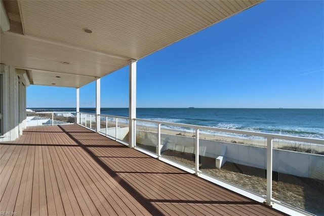 wooden deck featuring a beach view and a water view