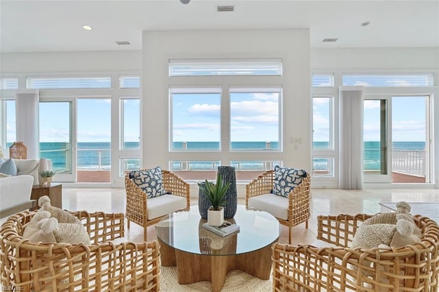 sunroom / solarium featuring a healthy amount of sunlight, a water view, and visible vents