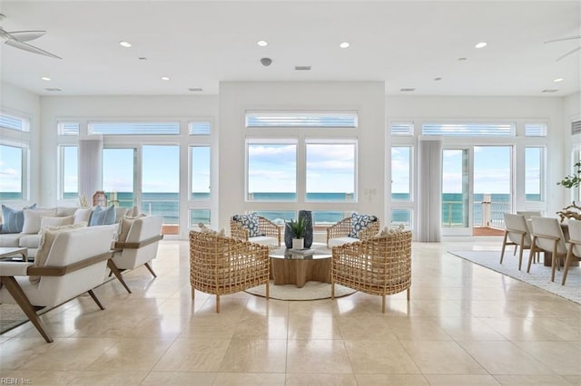 sunroom featuring a water view and a ceiling fan