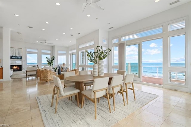 dining space featuring ceiling fan, a premium fireplace, visible vents, and light tile patterned flooring