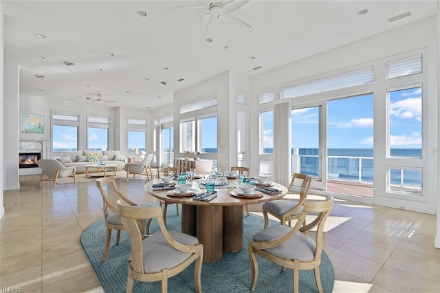 sunroom / solarium featuring visible vents, a fireplace, a ceiling fan, and a water view