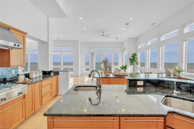 kitchen with dark stone countertops, stainless steel gas cooktop, tasteful backsplash, and a sink