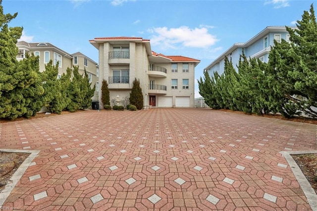 exterior space with decorative driveway, a tile roof, and an attached garage