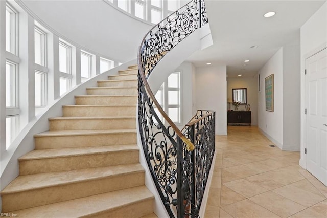 stairway with tile patterned floors, a high ceiling, baseboards, and recessed lighting