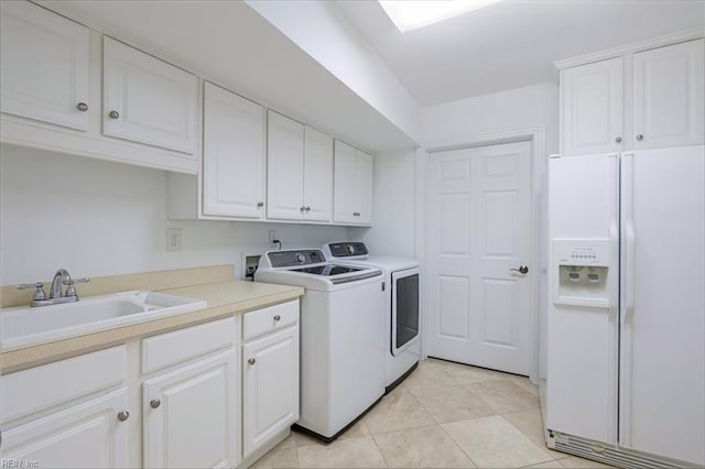 washroom with cabinet space, light tile patterned floors, washer and clothes dryer, and a sink