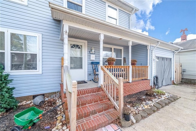 entrance to property with concrete driveway, a porch, crawl space, and an attached garage