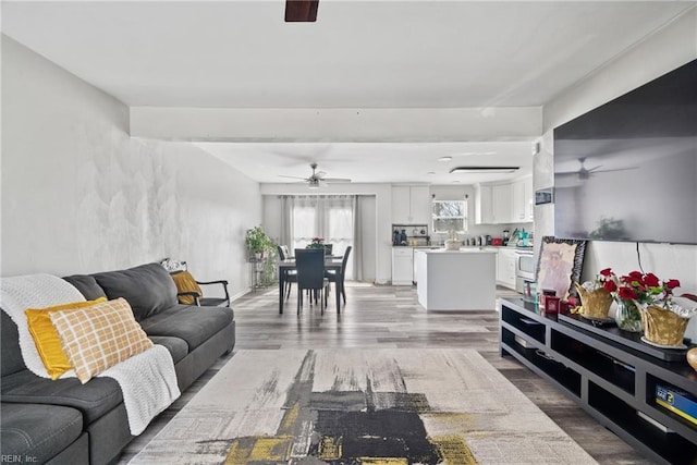 living area featuring light wood finished floors and a ceiling fan