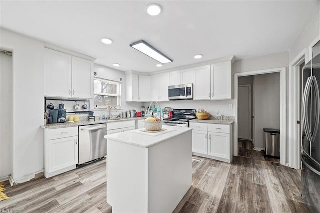 kitchen with light wood-style flooring, appliances with stainless steel finishes, white cabinetry, a sink, and recessed lighting