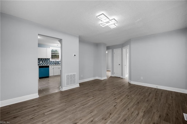 empty room with baseboards, a textured ceiling, visible vents, and wood finished floors