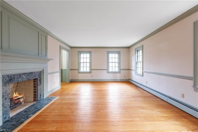 unfurnished living room with light wood finished floors, baseboards, a baseboard radiator, crown molding, and a fireplace