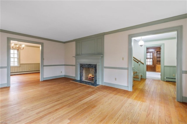 unfurnished living room with a baseboard radiator, crown molding, baseboard heating, and a premium fireplace