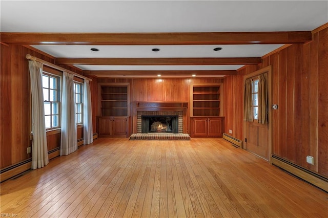 unfurnished living room with beam ceiling, wooden walls, baseboard heating, and light wood finished floors