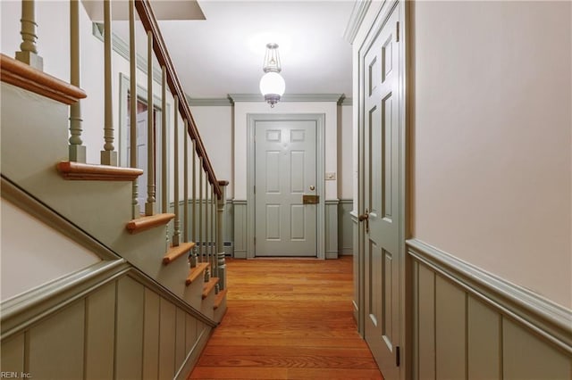 entryway with a decorative wall, a wainscoted wall, ornamental molding, stairway, and light wood-type flooring