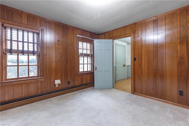 empty room with a baseboard heating unit, wood walls, and carpet