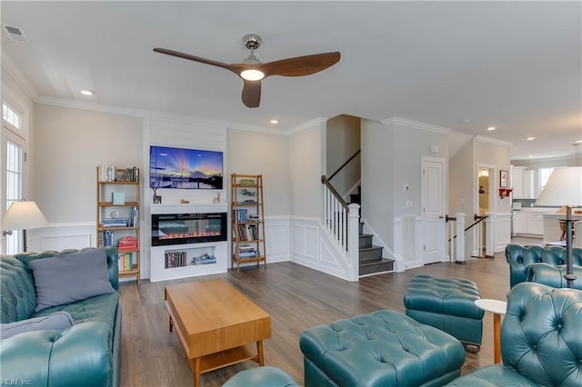 living room with a wealth of natural light, a glass covered fireplace, visible vents, and stairs