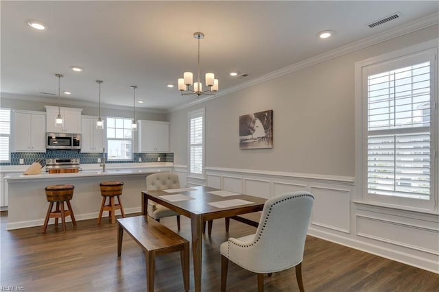 dining space with wainscoting, visible vents, dark wood-type flooring, and ornamental molding