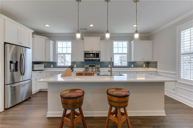 kitchen featuring stainless steel appliances, ornamental molding, and a wealth of natural light