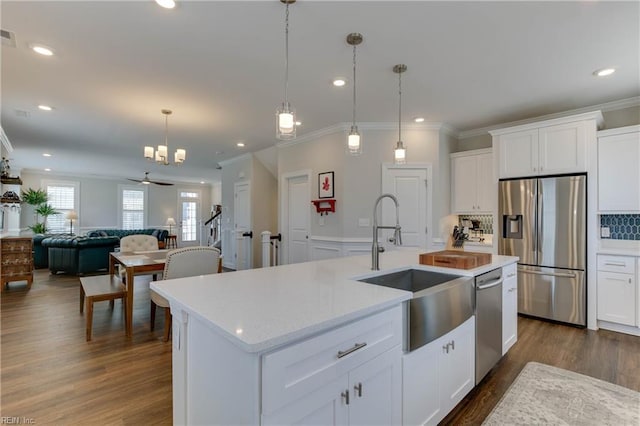 kitchen featuring dark wood finished floors, appliances with stainless steel finishes, open floor plan, hanging light fixtures, and a sink