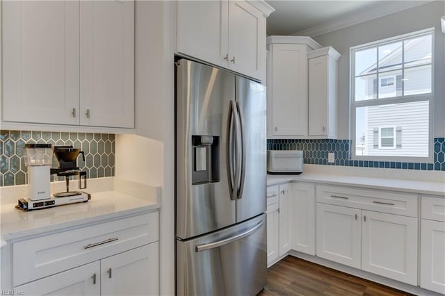 kitchen featuring a wealth of natural light, white cabinets, stainless steel fridge, and decorative backsplash