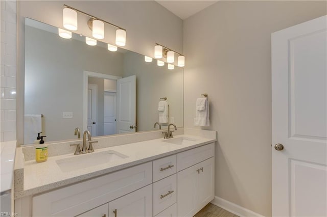 bathroom with a sink, baseboards, and double vanity