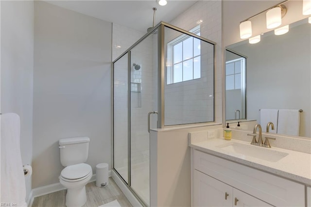 bathroom with a stall shower, baseboards, vanity, and toilet