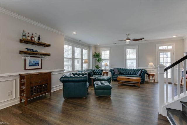 living area with dark wood-style floors, a wainscoted wall, a decorative wall, stairway, and ornamental molding